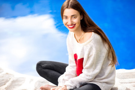 Portrait of a beautiful and cute woman dressed in sweater on the blue backgroundの写真素材
