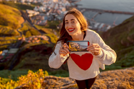 Young female traveler showing phone with photo of Santa Cruz cityscape on La Palma island in the morningの写真素材