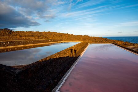 Volcanic pool on the salt manufaturing with pink salt water and sky reflection on La Palma islandの写真素材