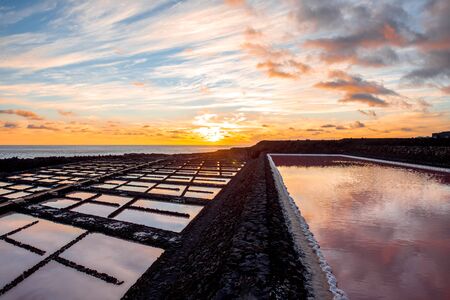 Volcanic pool on the salt manufaturing with pink salt water and sky reflection on the sunset on La Palma islandの写真素材