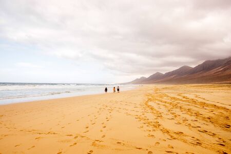 Cofete beach with people walking at the cloudy and foggy weather on Fuerteventura island in Spainの写真素材