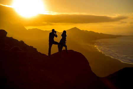 People silhouette on the mountain with beautiful view on Cofete beach on Fuerteventura island on the sunset in Spainの写真素材