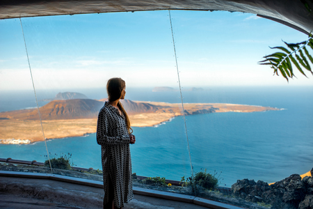 Woman looking on Graciosa island from El Rio viewpoint on Lanzarote island in Spainの写真素材