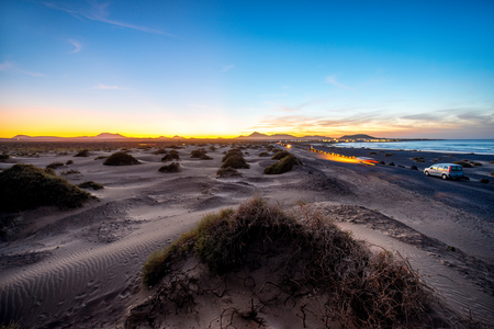 Famara sand dunes in the evening with car lights and beautiful sky on Lanzarote island in Spainの写真素材