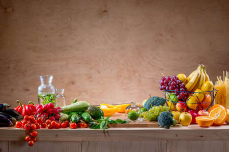 Table full of fruits and vegetables, drink and pasta with copy space on the wooden backgroundの写真素材