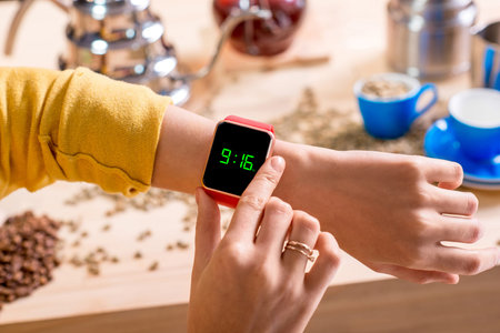 Female hands with smart watch showing time with alternative coffee stuff on the background