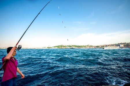 ISTANBUL - MAY 28, 2015: Turkish man fishing in Bosphorus waterway near Galata bridge in Istanbul. Hundreds of fishermen likes fishing in Istanbul all day longのeditorial素材