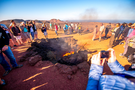TIMANFAYA PARK, LANZAROTE ISLAND, SPAIN - SIRCA JANUARY 2016: Tourits near volcanic heating system in Timanfaya park. This park is entirely made up of volcanic soil and was designed by Cesar Manriqueのeditorial素材