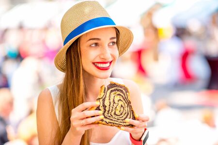 Young woman tasting traditional slovenian dessert Potica at the open market square in Ljubljana. Slovenian street food. Close up view with small depth of field.の写真素材