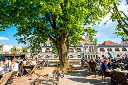 Ljubljana, Slovenia - May 6, 2016: People sit at the cafe near Ljubljanica river in the old city centre in Ljubljana. Ljubljana is the capital of Slovenia and famous european tourist destination.のeditorial素材