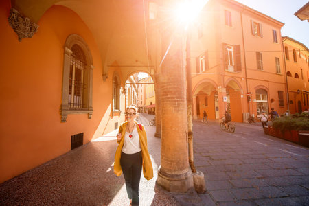 Young female student walking arched gallery on the way to university in Bologna city in Italy