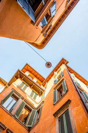 View from below on the old buildings with window shutters in Verona city center in Italy