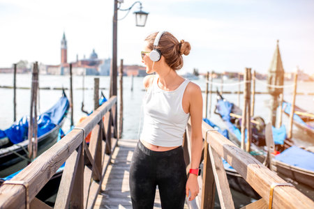 Young woman in sportswear enjoying great view standing on the pier in Venice. Morning exercise in the old town of Veniceの写真素材