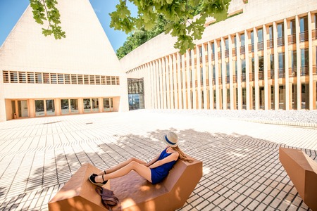 Vaduz, Liechtenstein - July 01, 2016: Young female tourist sits on the bench near the Parliament building in Vaduz, Liechtensteinのeditorial素材