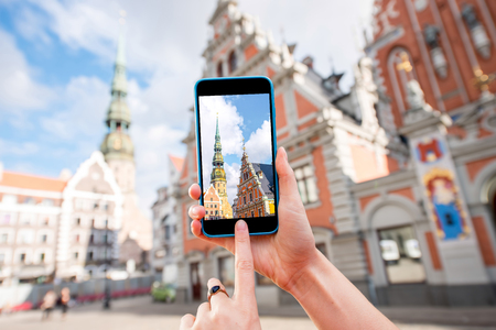 Photographing with smart phone famous houses of Blackheads and Peter church in the old town's center in Rigaの写真素材