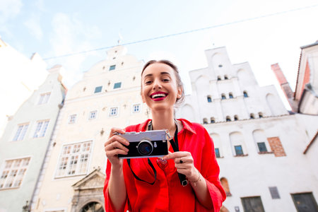 Portrait of a young female tourist with photo camera in front of the famous three brothers ancient...