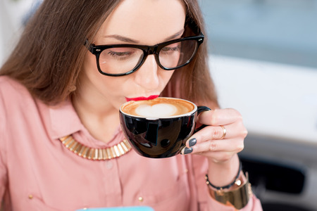 Close-up view on the woman drinking cappuccinoの写真素材