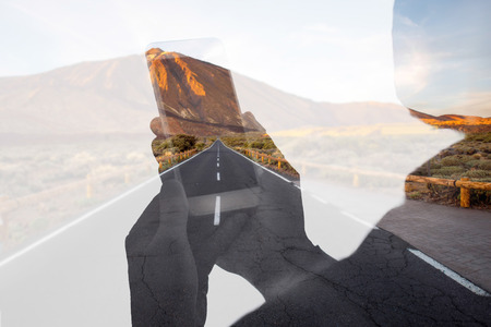 Holding phone on the deserted road backgroundの写真素材