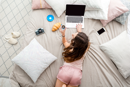 Woman with laptop on the bedの写真素材