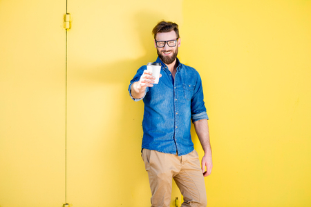 Man with coffee on the yellow backgroundの写真素材