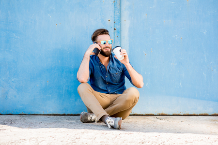 Man with phone on the blue backgroundの写真素材
