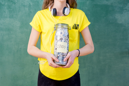 Woman holding a bottle full of money savings for studyの写真素材