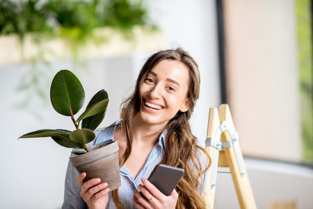 Woman with phone and flowerpotの写真素材