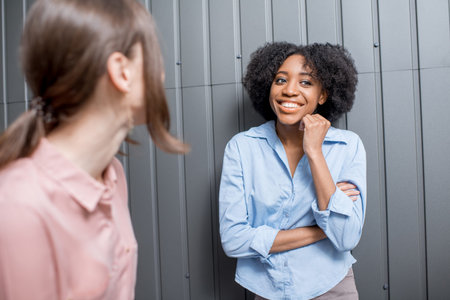 Coworkers dressed casually talking indoors on the wall background