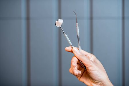 Holding dental tools on the gray wall backgroundの写真素材