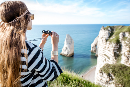 Woman with binoculars on the rocky coastlineの写真素材