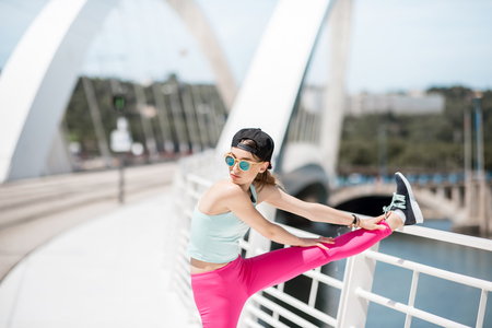 Woman in sportswear outdoors on the modern bridgeの写真素材