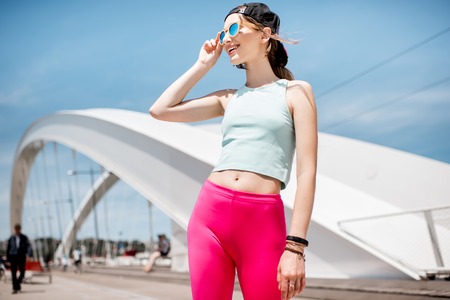 Woman in sportswear outdoors on the modern bridgeの写真素材