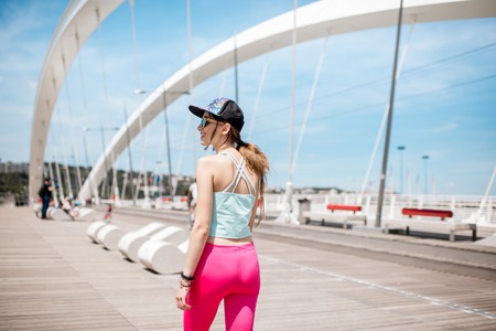Woman in sportswear outdoors on the modern bridgeの写真素材