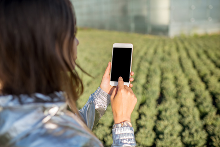 Holding a smart phone at the green houseの写真素材