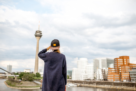 Young woman enjoying great view on the harbor with modern buildings and television tower in Dusseldorf city, Germanyの写真素材