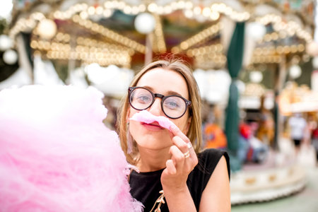 Woman with cotton candy at the amusement parkの写真素材