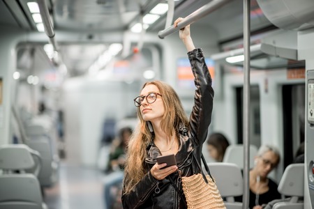 Lifestyle portrait of a young businesswoman standing with smart phone at the modern trainの写真素材