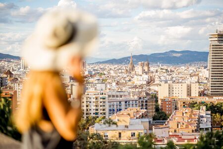Young woman tourist in hat enjoying great cityscape view on Barcelona. Woman is out of focusの写真素材