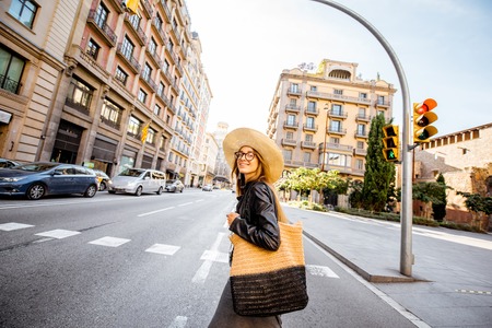 Woman tourist in hat crossing the street during the morning light in Barcelona cityの写真素材