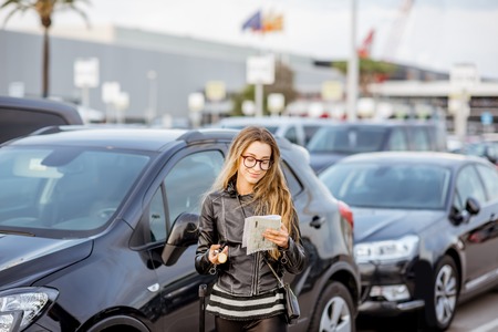 Young woman looking on the rental contract standing outdoors on the airport car parkingの写真素材