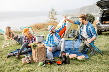 Multi ethnic group of friends dressed casually having a picnic during the outdoor recreation with...