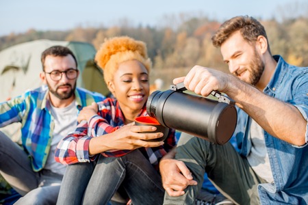 Friends pouring tea with hiking thermos during the outdoor recreationの写真素材