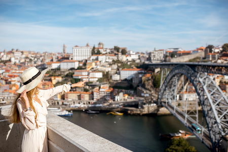 Young woman tourist enjoying beautiful cityscape background with famous bridge in Porto city, Portugalの写真素材