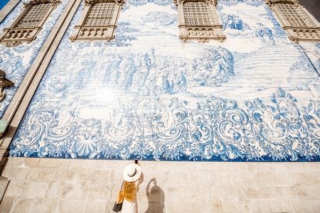 Young woman tourist photographing famous portuguese blue ceramic tiles on the facade traveling in Porto city, Portugalの写真素材