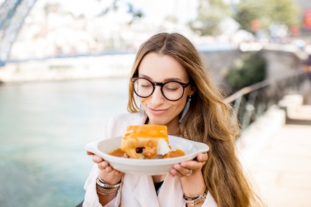 Portrait of a young woman with traditional portuguese sandwich with meat called francesinha on the landscape background with bridge in Porto city, Portugalの写真素材