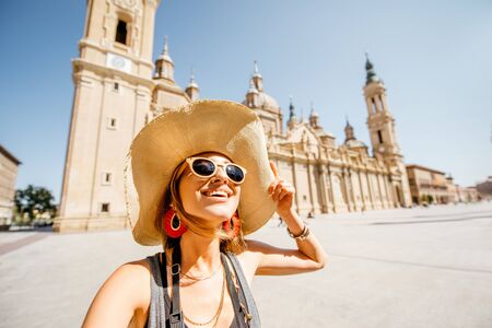 Young woman tourist making selfie photo in front of the famous cathedral on the central square during the sunny weather in Zaragoza city, Spainの写真素材