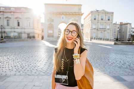 Young woman talking with phone on the street near the famous Triumphal Arch during the morning light in Montpellier city, Franceの写真素材