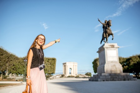 Portrait of a young woman tourist showing Louis statue at the famous Peyrou park during the morning light in Montpellier city in Franceの写真素材