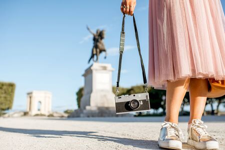 Woman holding photocamera at the famous Peyrou park in front of the Louis statue during the morning light in Montpellier city in Franceの写真素材
