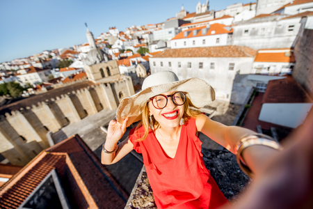 Portrait of a young woman tourist in red dress on the old city background traveling in Coimbra city in the central Portugalの写真素材